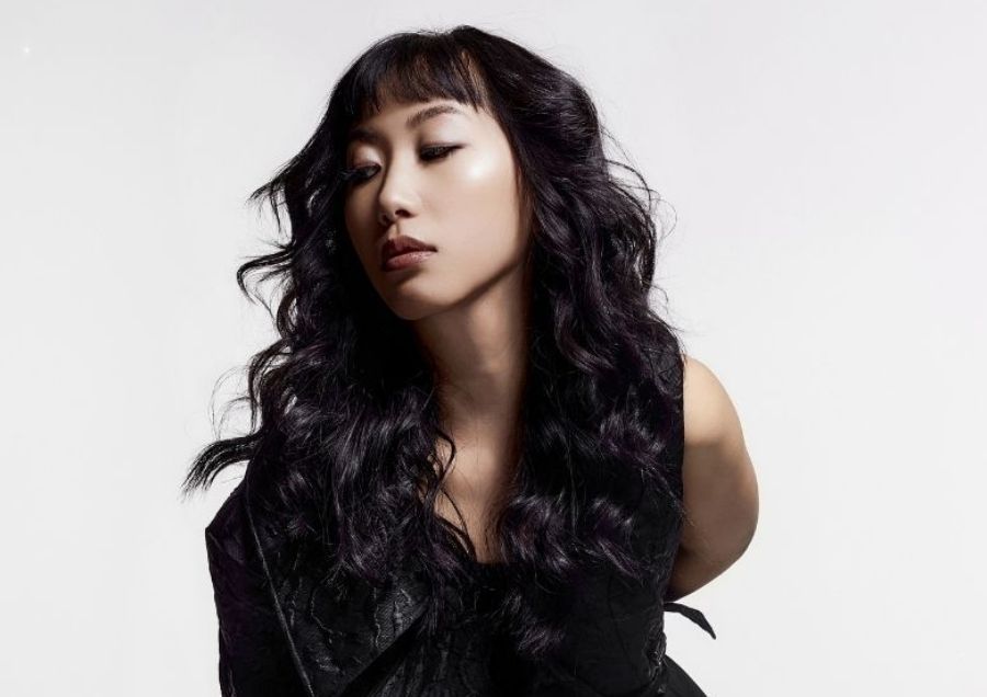 Modèle féminin avec une coupe tendance sur cheveux longs et ondulés sombres, stage de perfectionnement Cyléa Formations.